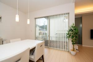 a white dining room with a table and a potted plant at ISE Resort 綾 UZ1 in Ise