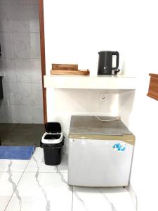 a small refrigerator in a kitchen with a trash can at Lestari Homestay Jimbaran in Jimbaran