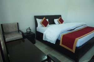 a bedroom with a large bed and a chair at Apple Hilltop Homestay in Chaubattia