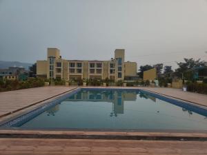 a large swimming pool in front of a building at Ammora Resort in Kārli