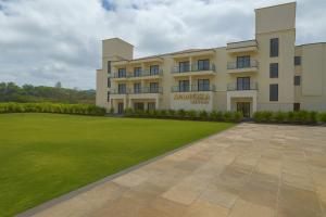 a building with a green lawn in front of it at Ammora Resort in Kārli