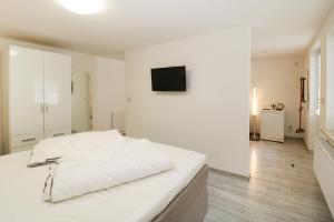 a white bedroom with a white bed and a television at Koserow Hotel Wald und Meer in Koserow