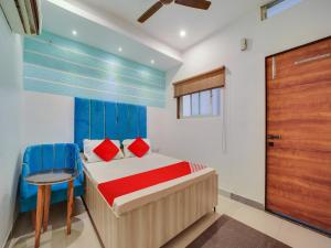 a bedroom with a bed and a chair and a door at Hotel O Jagdamba Hotel in Bhopal