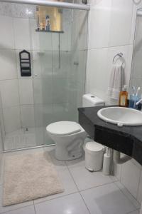 a bathroom with a toilet and a shower and a sink at Aconchego na praia in Ilhéus