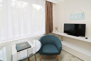 a living room with a table and a chair and a television at Koserow Hotel Wald und Meer in Koserow