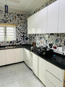 Eine Küche mit weißen Schränken und schwarz-weißer Tapete in der Unterkunft Stan - Haven Apartments ASOKORO in Asokoro
