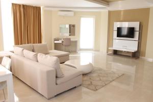 a living room with a white couch and a tv at Bruxelles Guesthouse Craiova in Craiova
