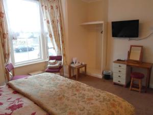 a bedroom with a bed and a television and a window at Greystones in Skegness