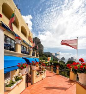 a balcony of a hotel with flowers and a flag at Hotel Weber Ambassador in Capri