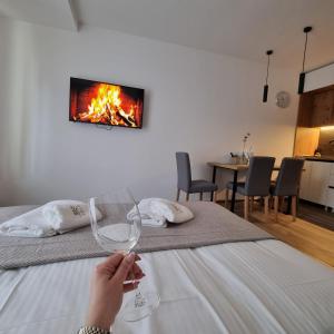 a person holding a wine glass in front of a bed at SKYLINE apartments Kopaonik in Kopaonik