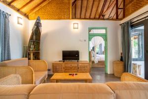 a living room with a couch and a tv at Breathe Villa Meno in Gili Meno