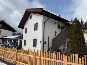 a white house behind a wooden fence at Appartement Steinbergrose in Leogang