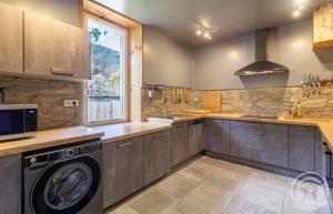 a large kitchen with a washer and a window at Aubépine in Cadéac
