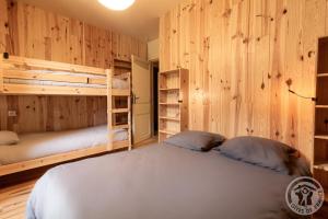 a bedroom with two bunk beds and wooden walls at Aubépine in Cadéac