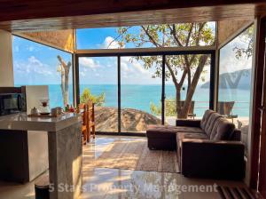 a living room with a couch and a view of the ocean at Epic Views Cabins - Ocean or Mountains, your choice in Ko Phangan