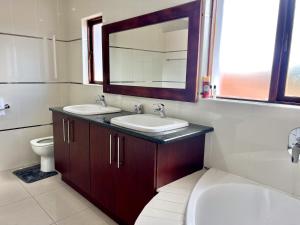 a bathroom with two sinks and a toilet and a mirror at Thetsane Ridge in Maseru +40 photos