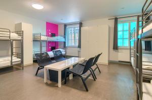 a room with a table and chairs and bunk beds at Hostel-Marburg-one Dorms in Marburg an der Lahn