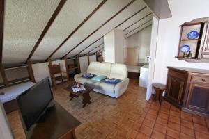 a living room with a couch and a tv at Hostdomus - Bi Level Apartment in Pragelato