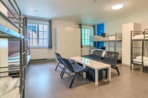 a room with a table and chairs and bunk beds at Hostel-Marburg-one Dorms in Marburg an der Lahn
