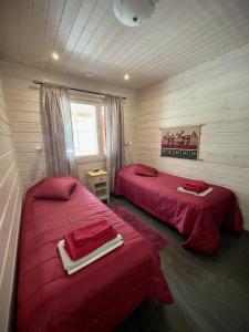 two beds in a room with red sheets at Lumilyhty B in Äkäslompolo