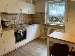 a kitchen with white cabinets and a table and a window at Landhaus Friedel in Baiersbronn