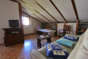 a living room with two couches and a tv at Hostdomus - Bi Level Apartment in Pragelato