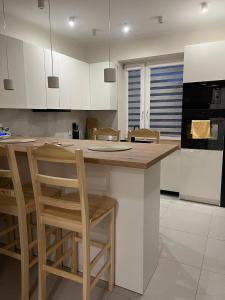 a kitchen with white cabinets and a island with bar stools at Borówkowy domek in Janik +8 photos
