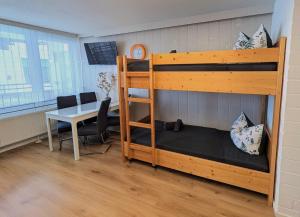 a bedroom with a bunk bed with a desk and a table at Sylva Apartment in Sankt Englmar