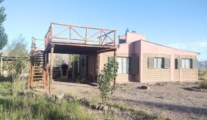 a brick house with a wooden structure in a field at Casa Munay para dos personas in Uspallata
