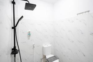 a white tiled bathroom with a toilet and a spotlight at Tripletree Kenaro Hotel in Blimbing +38 photos