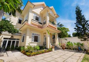 a large yellow house with a porch at AnNam Village 4 in Vung Tau