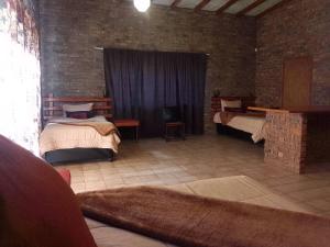 a room with two beds and a brick wall at Mountain Guesthouse in Pretoria