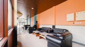 a waiting room with black leather couches and tables at Tripletree Kenaro Hotel in Blimbing