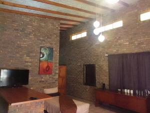 a room with a bed and a tv on a brick wall at Mountain Guesthouse in Pretoria