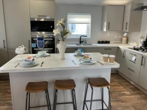 a kitchen with a large white island with two stools at Seafront Serenity Lodge in Newbiggin-by-the-Sea