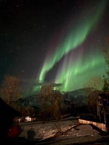 an aurora in the night sky over a town at Big cabin in Lyngen Fjords in Jægervatnet