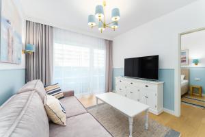 a living room with a couch and a tv at FARO Apartamenty Polanki Aqua 4 BASENY w cenie POOLS im Preis in Kołobrzeg +198 photos