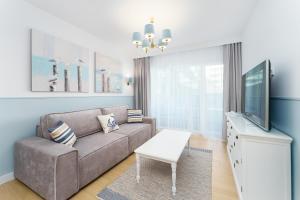 a living room with a couch and a flat screen tv at FARO Apartamenty Polanki Aqua 4 BASENY w cenie POOLS im Preis in Kołobrzeg
