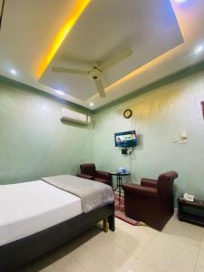 a bedroom with a bed and two chairs and a tv at AL FANAR REST HOUSE LLC in Ras al Khaimah