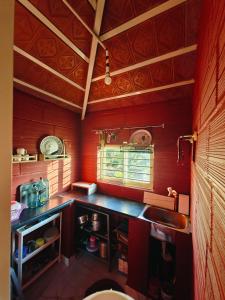 a kitchen with red walls and a sink and a window at Lalitha Farm Stay in Tumkūr