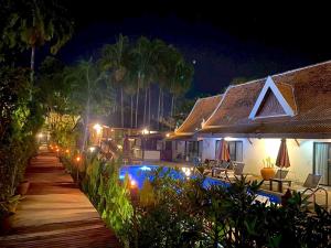 a house with a pathway leading to a swimming pool at night at Sea Pines & Liberg in Nai Yang Beach