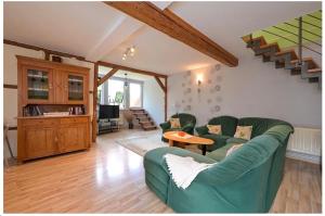 a living room with two green couches and a table at Gerstels Ferienhof in Hörselberg-Hainich