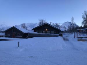 a house covered in snow in front of it at Big cabin in Lyngen Fjords in Jægervatnet