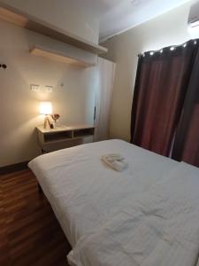 a bedroom with a white bed and a table with a lamp at Goshen Haus in Baclayon