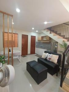 a living room with a black couch and a staircase at Goshen Haus in Baclayon