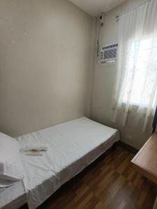a small bedroom with a bed and a window at Goshen Haus in Baclayon
