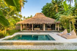 a resort with a swimming pool and a thatch hut at Breathe Villa Meno in Gili Meno