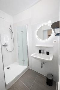 a white bathroom with a shower and a sink at Gästehaus Kühnle in Bad Wildbad +35 photos