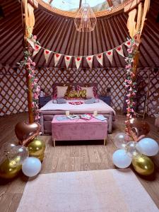 a room with a bed and balloons in a yurt at Glamp and Tipple Ltd in Great Ellingham