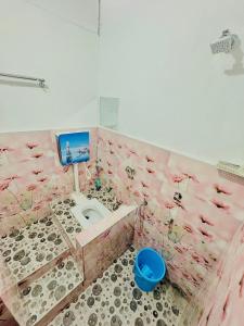 a pink bathroom with a toilet with birds on the wall at Mannat Lodge in Hailākāndi